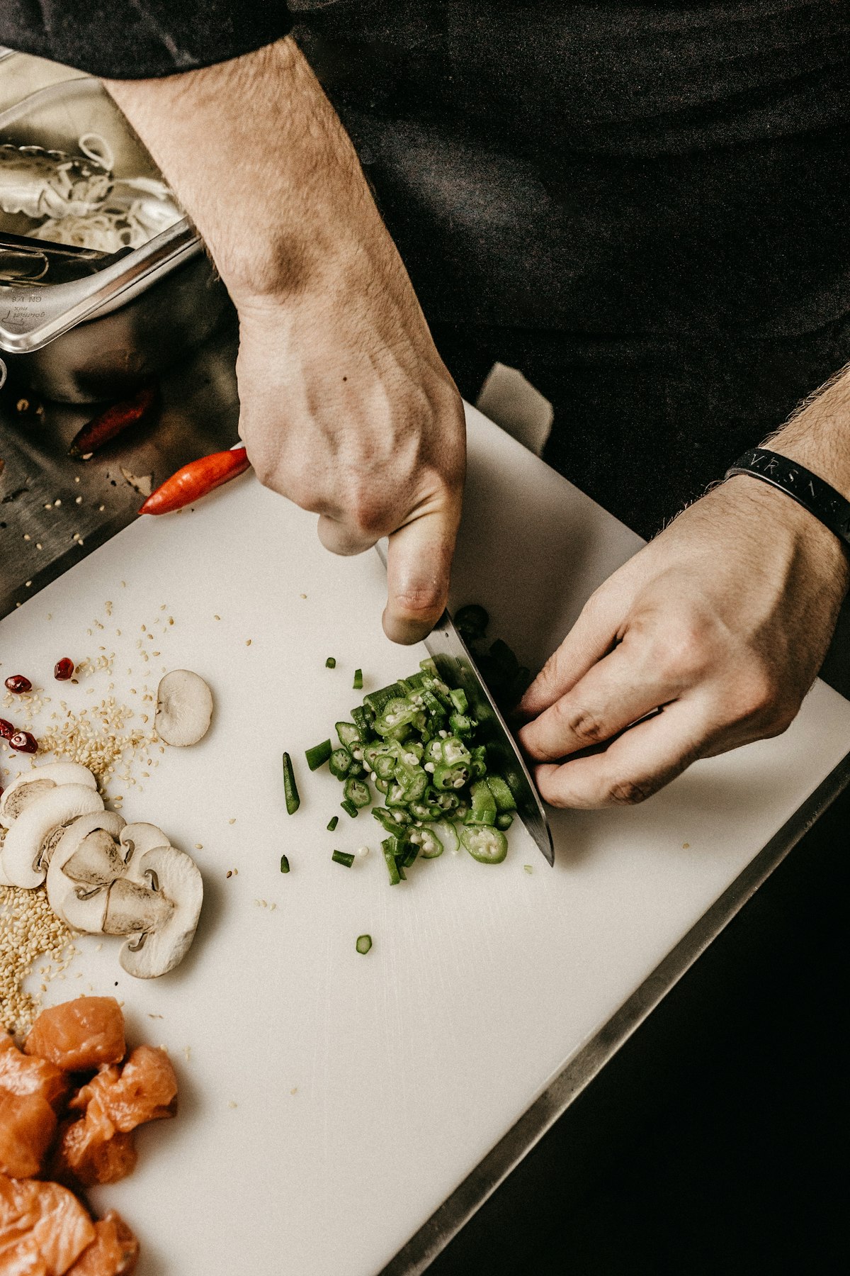 Un cuisinier émince des légumes sur une planche