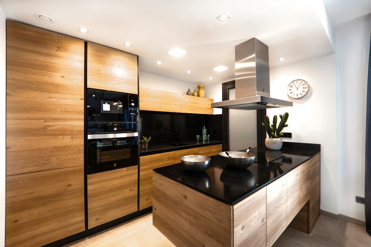 Cuisine aux façades en bois, îlot central et plan de travail sombre